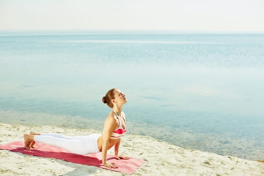 Fit woman doing stretching exercise by the seaside