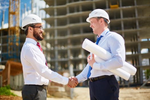 Two happy architects handshaking after striking deal
