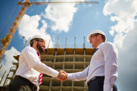 Two handsome architects approving deal by handshake