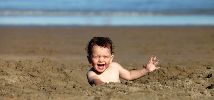 A toddler playing in the sand at the beach.