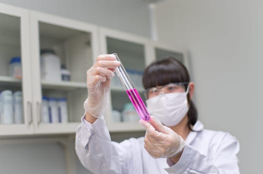 an Asian analyst is observing a chemical tube
