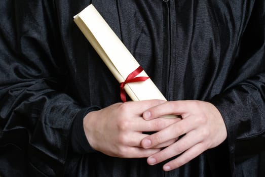 A macro shot of a graduating student holding their diploma proudly.
