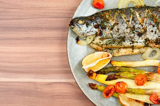 Whole river trout baked with white asparagus and tomatoes. Top view.