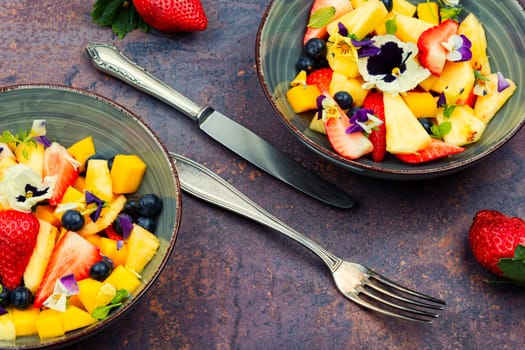 Delicious summer salad with field pansies and fruit