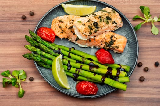 Grilled trout and green asparagus on a wooden table