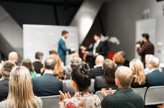 Business team leader receiving award prize at best business project competition event. Business and entrepreneurship award ceremony theme. Focus on unrecognizable people in audience