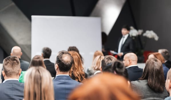 Speaker giving a talk in conference hall at business event. Rear view of unrecognizable people in audience at the conference hall. Business and entrepreneurship concept