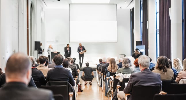 Business team leader receiving award prize at best business project competition event. Business and entrepreneurship award ceremony theme. Focus on unrecognizable people in audience