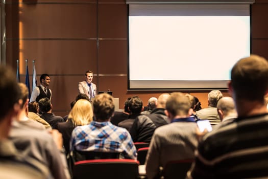 Speaker giving a talk in conference hall at business meeting event. Rear view of unrecognizable people in audience at the conference hall. Business and entrepreneurship concept.