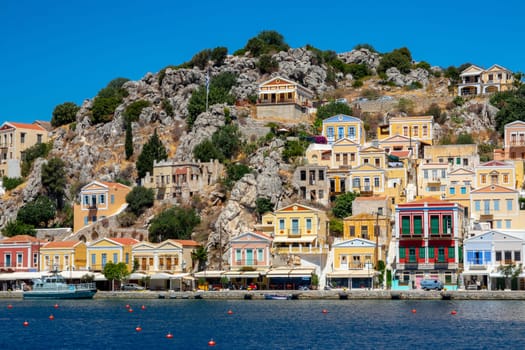 SYMI, Greece - JUN 03, 2021. The harbour of Symi town with the districts of Chorio and Gialos is one of the most beautiful and romantic in the whole Aegean. Colourful mansions stretch up the steep slopes.