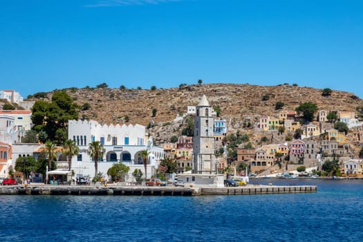 SYMI, Greece - JUN 03, 2021. The harbour of Symi town with the districts of Chorio and Gialos is one of the most beautiful and romantic in the whole Aegean. Colourful mansions stretch up the steep slopes.