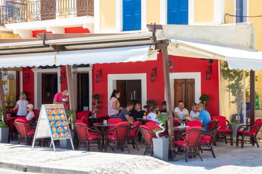 SYMI, Greece - Jun 03, 2021. A restaurant on the harbour promenade of Symi town where tourists linger. Most beautiful and romantic district in the whole Aegean.