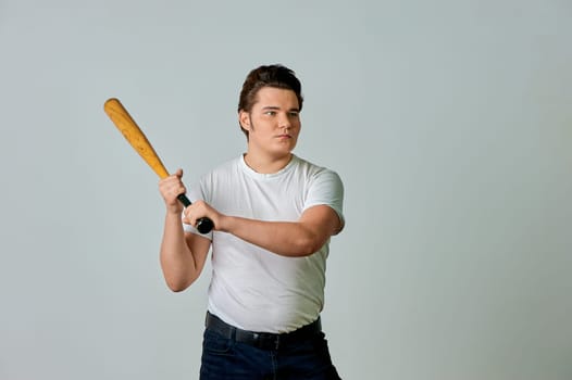 A man with a bat in his hands swings on a gray background. High quality photo