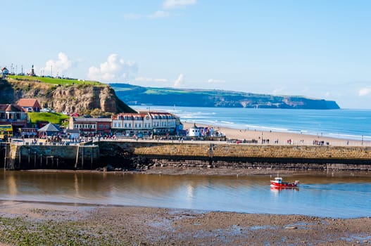 Scenic view of Whitby city and pier in sunny autumn day.Whitby is a seaside town and port in North Yorkshire, UK. Its attraction as a tourist destination is enhanced by its association with the world famous horror novel Dracula, written by Bram Stoker