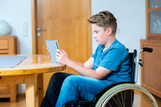 disabled boy in wheelchair chatting in the internet with tablet PC