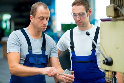 two young worker in factory on the machine