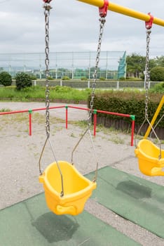 Colorful swings at a childrens park on a dark cloudy day.