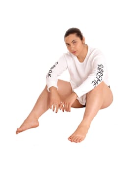 A young pretty woman sitting on the floor in a short white shirt, barefoot,.isolated for white background..