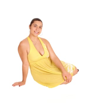 A smiling young woman in a yellow dress sitting on the floor, isolated.for white background..