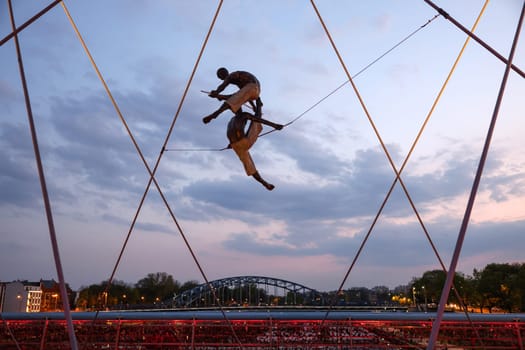 Cracow, Poland - May 2, 2022: Balancing sculptures between sky and water by Jerzy Kedziora over the Kornatka footbridge over the Vistula River in Krakow