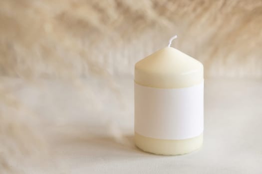 Candle with blank paper label on white table with dried pampas grass, Close up, copy space. Minimal brand packaging mock up. Home decoration, minimal interior, Bohemian or scandinavian style..