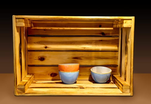 Several ceramic bowls stand very decoratively in a wooden box.