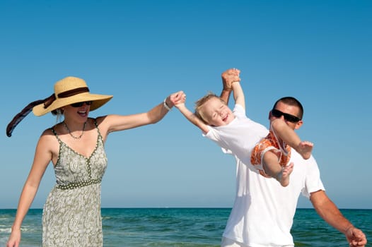 Happy parents and child having fun spending time at the beach