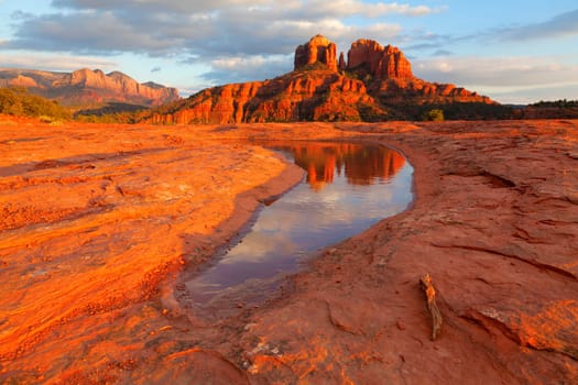 Cathedral Rock in the distance is reflected in a pool of water at sunset