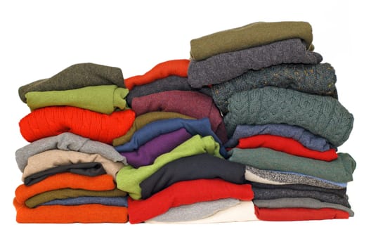 Stack of chunky Irish wool cable knit, Cashmere and Aran winter men's sweaters in fall and winter colours against white