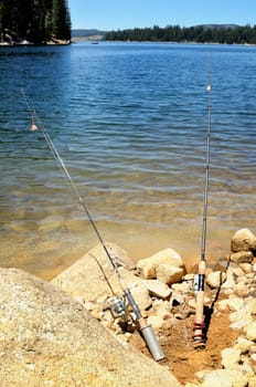 Two fishing rods  with lake on the background at bright sunny day