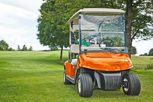 An image of a orange golf car in the green