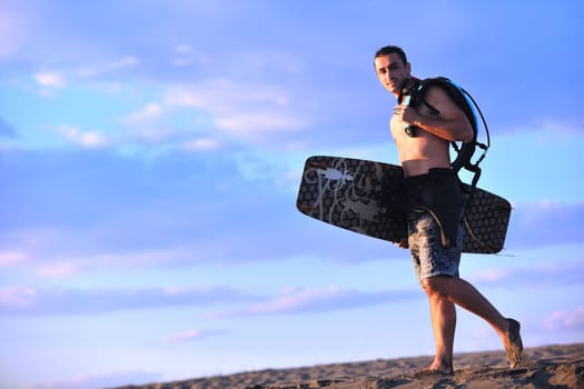 Portrait of a strong young  surf  man at beach on sunset in a contemplative mood with a surfboard