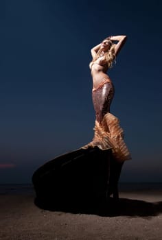 woman in exotic dress standing on a boat on the beach