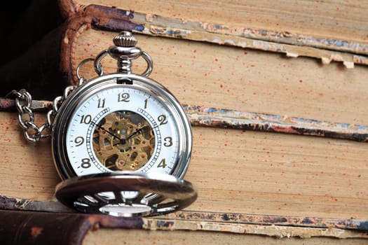 Vintage pocket watch with open lid on background with old books