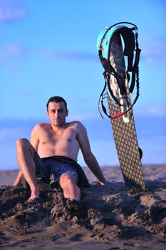 Portrait of a strong young  surf  man at beach on sunset in a contemplative mood with a surfboard