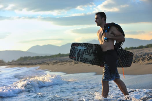 Portrait of a strong young  surf  man at beach on sunset in a contemplative mood with a surfboard