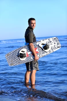 Portrait of a strong young  surf  man at beach on sunset in a contemplative mood with a surfboard