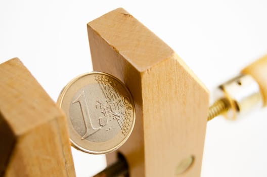 One euro coin under pressure in  a wooden clamp