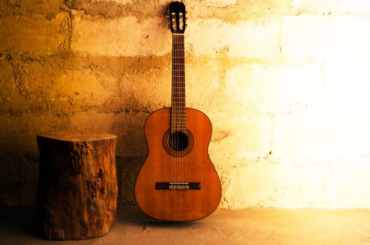 Acoustic guitar on old wall and stump with copyspace