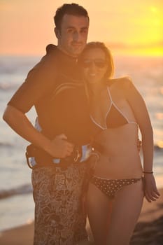 romantic couple in surf wear posing at beach on sunset at summer season
