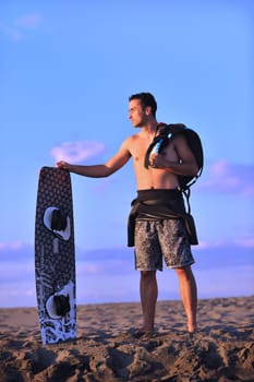 Portrait of a strong young  surf  man at beach on sunset in a contemplative mood with a surfboard