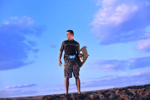 Portrait of a strong young  surf  man at beach on sunset in a contemplative mood with a surfboard