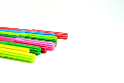 A few colourful pens agaist a white background . Maybe used to signify art , vibrancy , colour or anything creative.