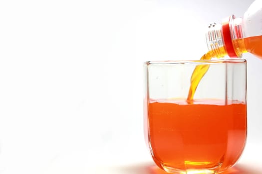 Pouring an orange beverage into a glass , the orange is vibrant and gives the image an extra kick.