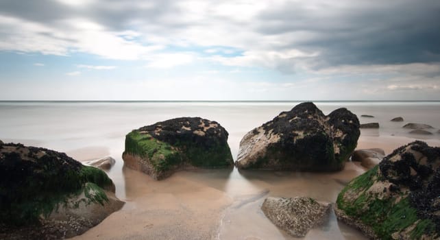 Beach rocks long exposure with cloudy sky