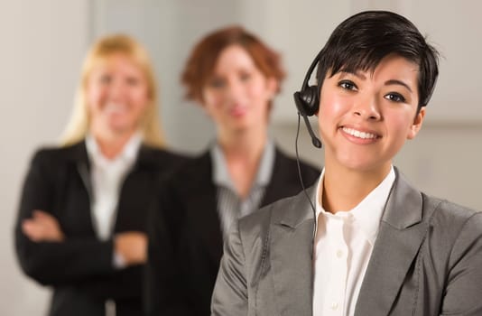 Pretty Hispanic Businesswoman with Colleagues Behind in an Office Setting.