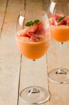photo of delicious ham and melon cocktail appetizer on wooden table