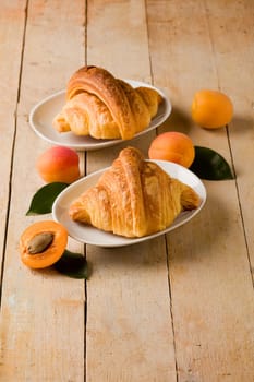 photo of delicious golden croissants with apricot marmalade on wooden table