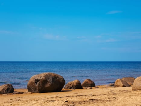 Sea rocky beach in sunny day, blue cloudy sky
