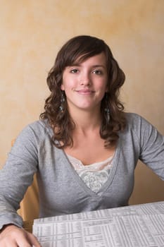 Pretty brunette reading the morning newspaper at the kitchen table